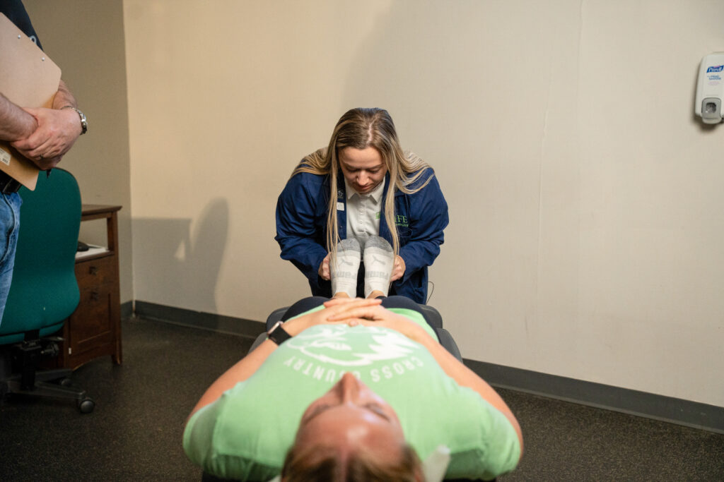 Student performing chiropractic adjustment at patient's feet
