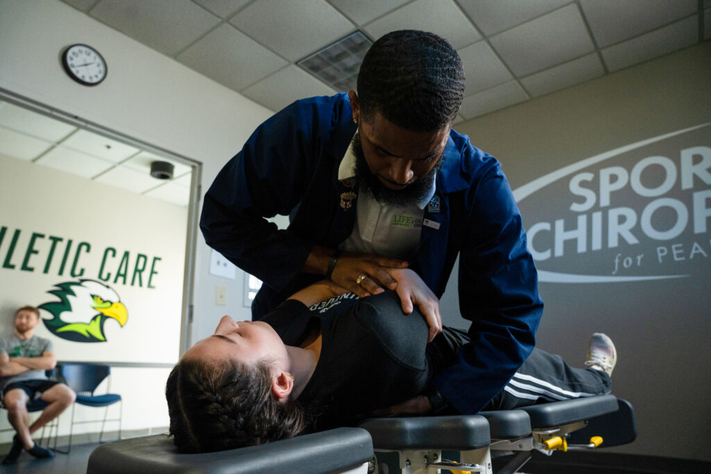 Student performs chiropractic adjustment on patient's back